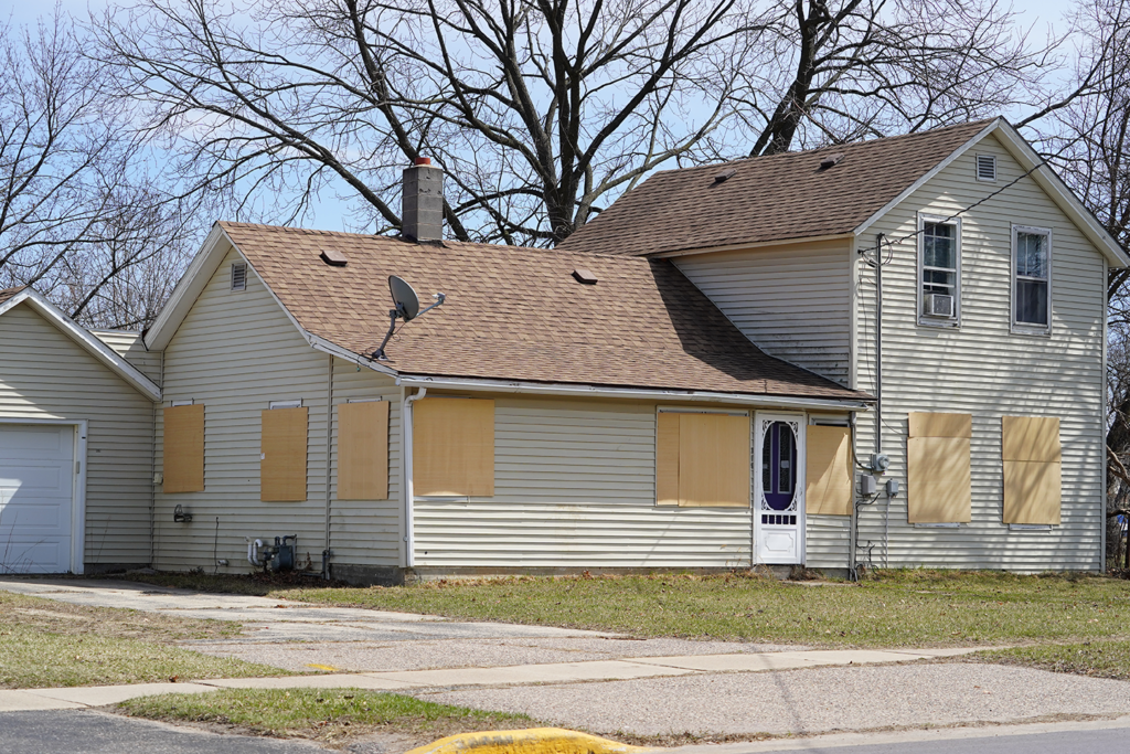Boarded-up distressed house with plywood over the windows
