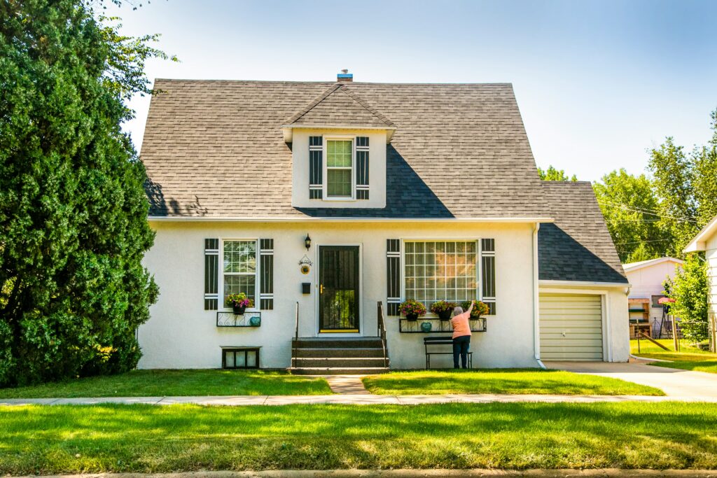 White single-storey family home with a green lawn and mature trees